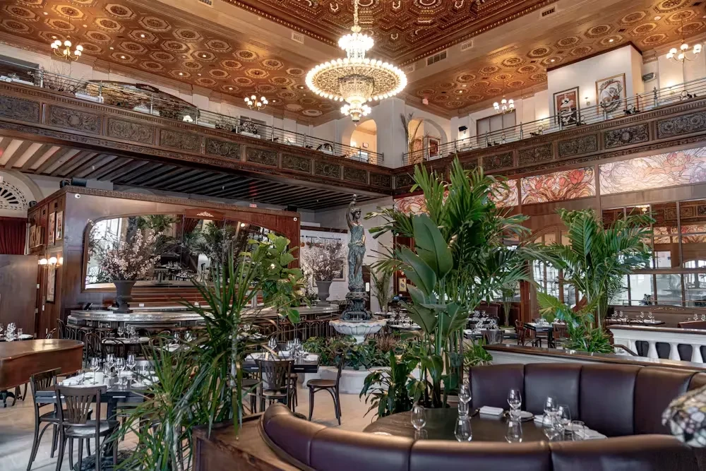 Ornate, luxurious restaurant interior with fountain, mezzanine, and grand piano.