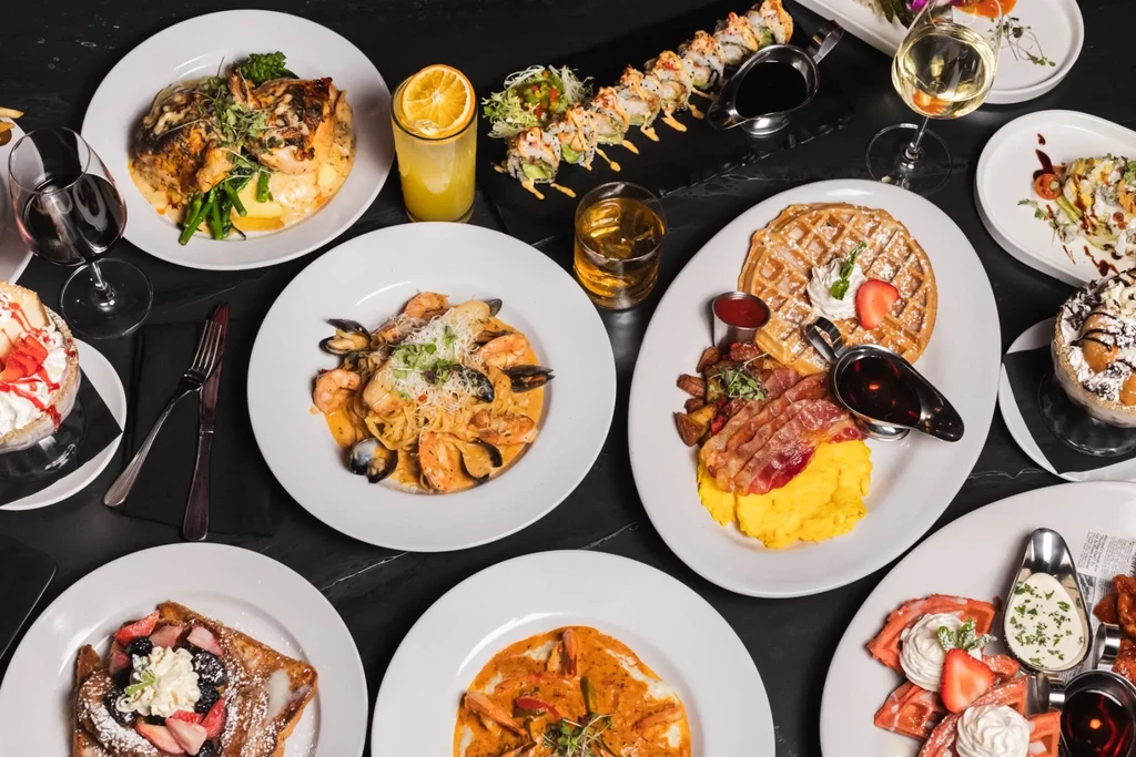 A tabletop view of several full plates of seafood, breakfast, and sushi.