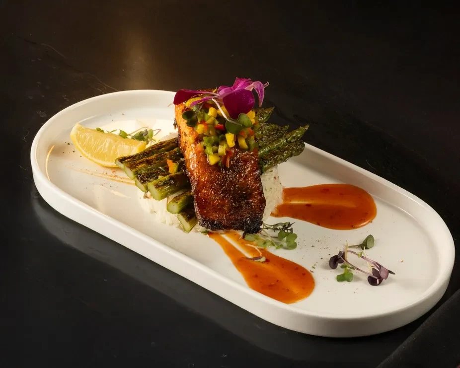 Pan-seared salmon with mango salsa, asparagus, rice, and sauce.