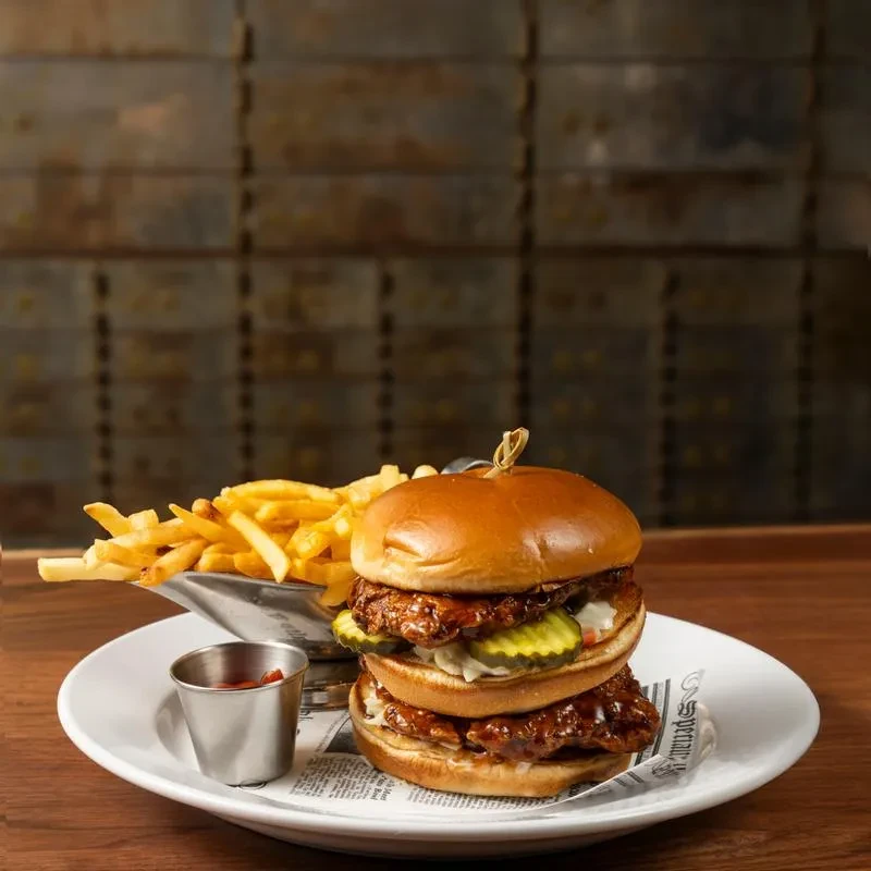 Double-decker chicken sandwich with fries and a cup of ketchup.