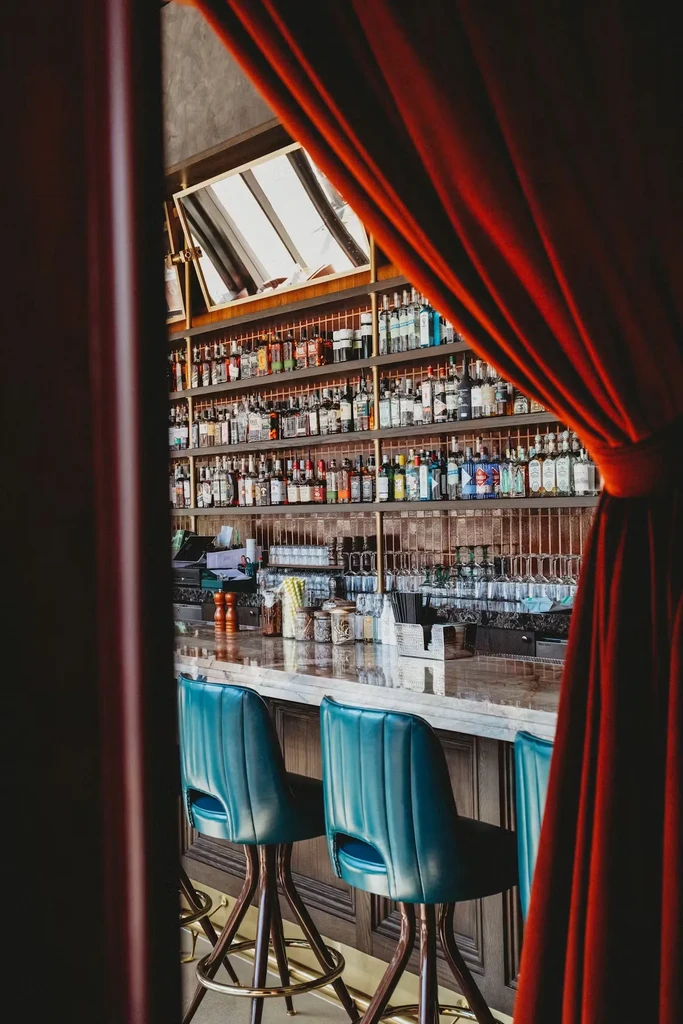 Interior view of a well-stocked bar with red velvet curtain.