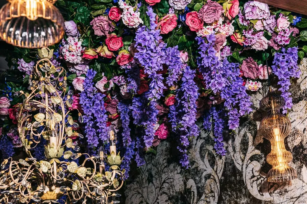 Ornate interior with floral arrangement, chandeliers, and decorative wall.