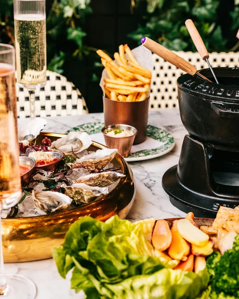 Luxurious dining setup with oysters, champagne, french fries, and fondue.
