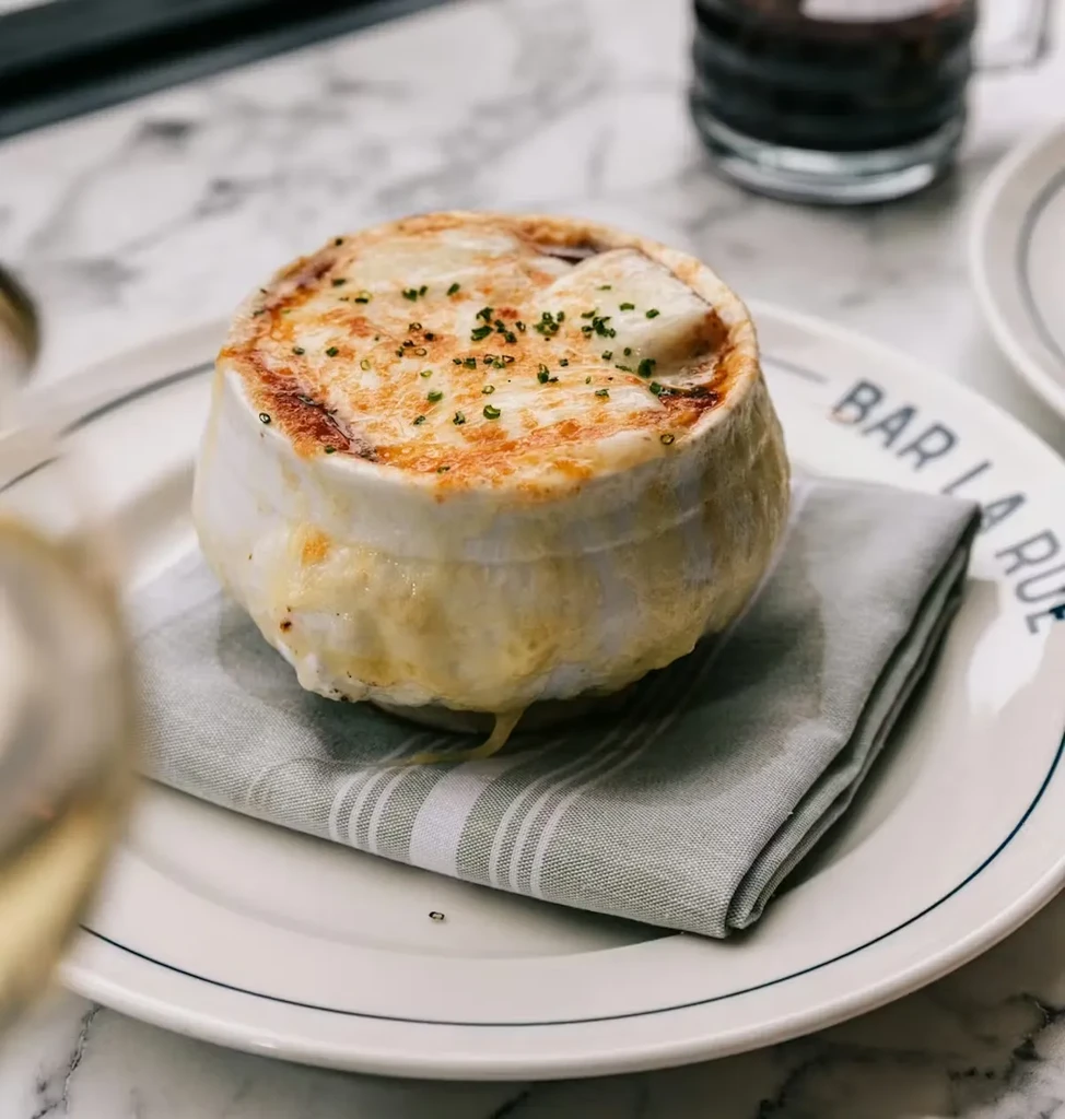 French onion soup with melted cheese in a white ceramic crock.