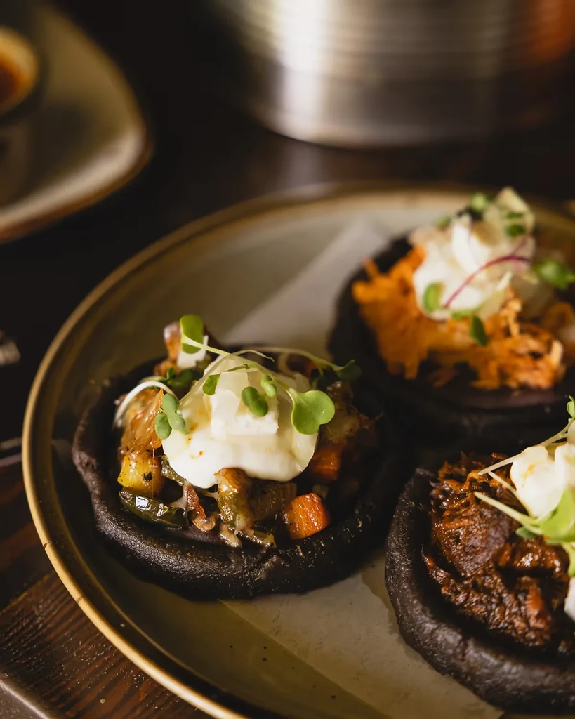 Black corn sopes with various toppings, sour cream, and microgreens.