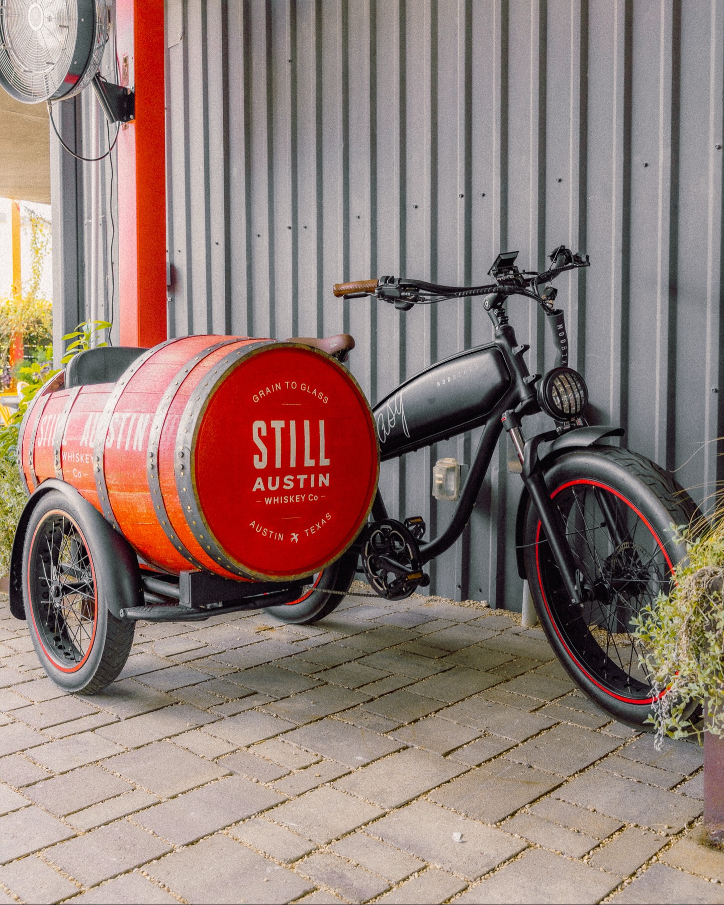 Black e-bike with red whiskey barrel sidecar.