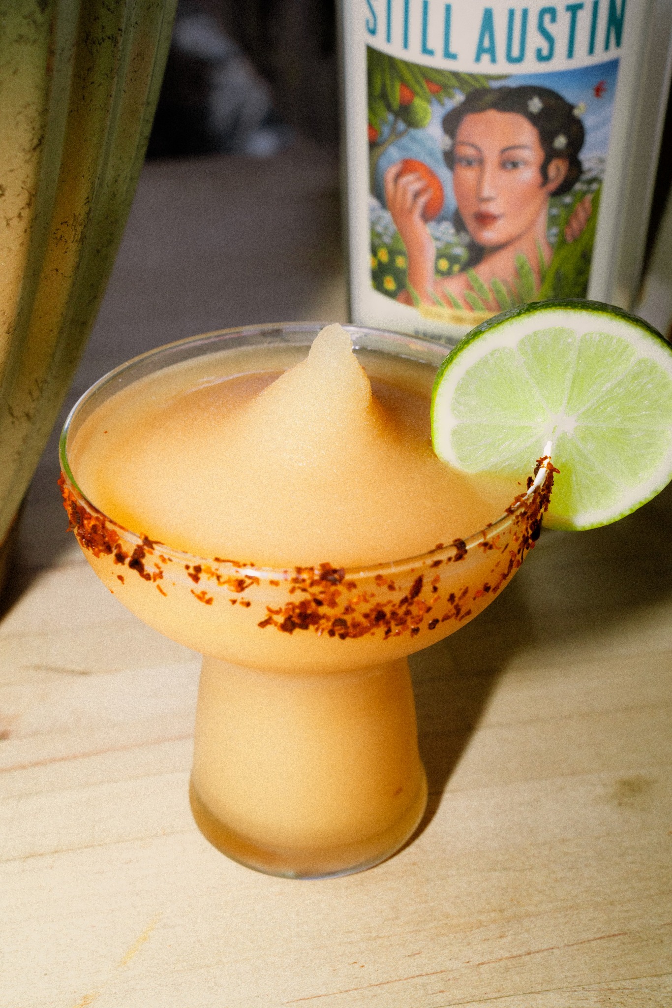 Frozen orange drink with chili rim and lime wedge.