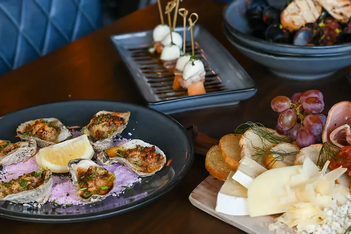 Baked oysters, mozzarella skewers and cheese board on wooden table