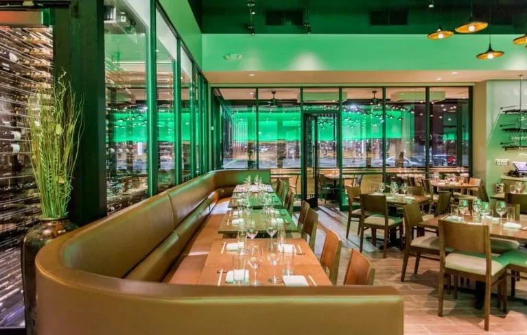 Interior view of a modern restaurant with booths, tables, and a wine wall.