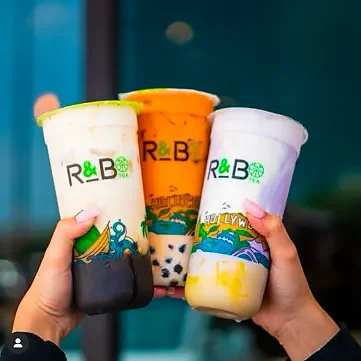 Three colorful bubble teas with boba held up together