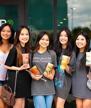 Five customers holding drinks outside the shop entrance