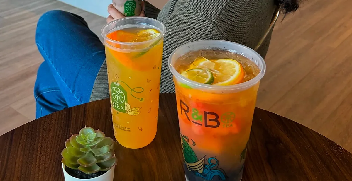 Two iced fruit teas with citrus slices on wooden table