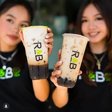 Two staff members holding brown sugar and milk teas