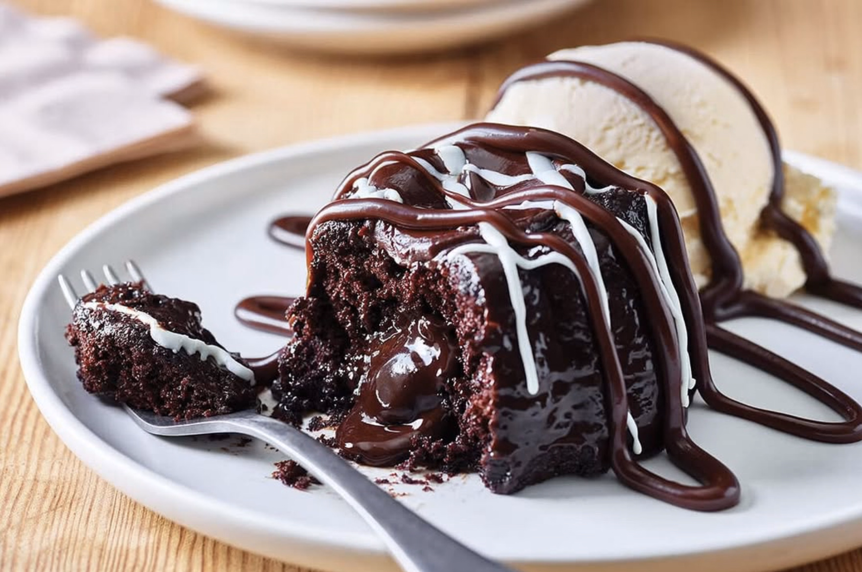 Decadent molten chocolate cake with ice cream and chocolate drizzle.