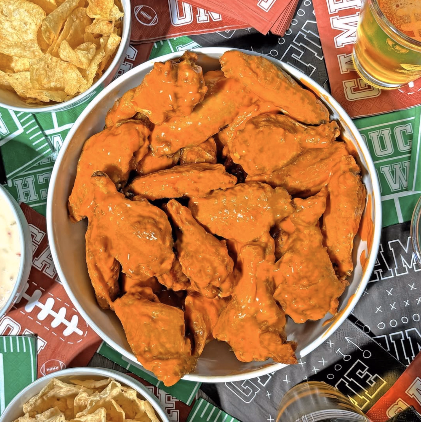 Game day Buffalo wings tossed in spicy sauce, served with chips and dips.