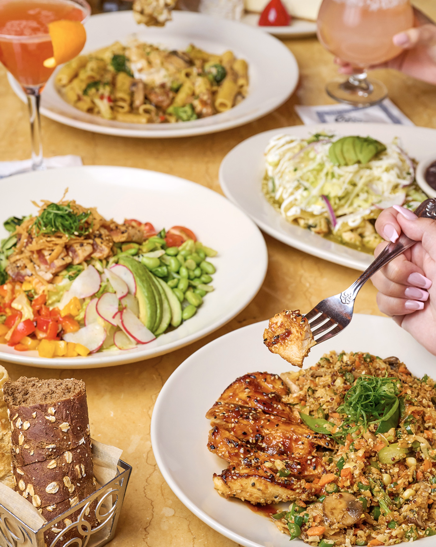 Colorful meal spread with chicken, quinoa salad, and pasta dishes.