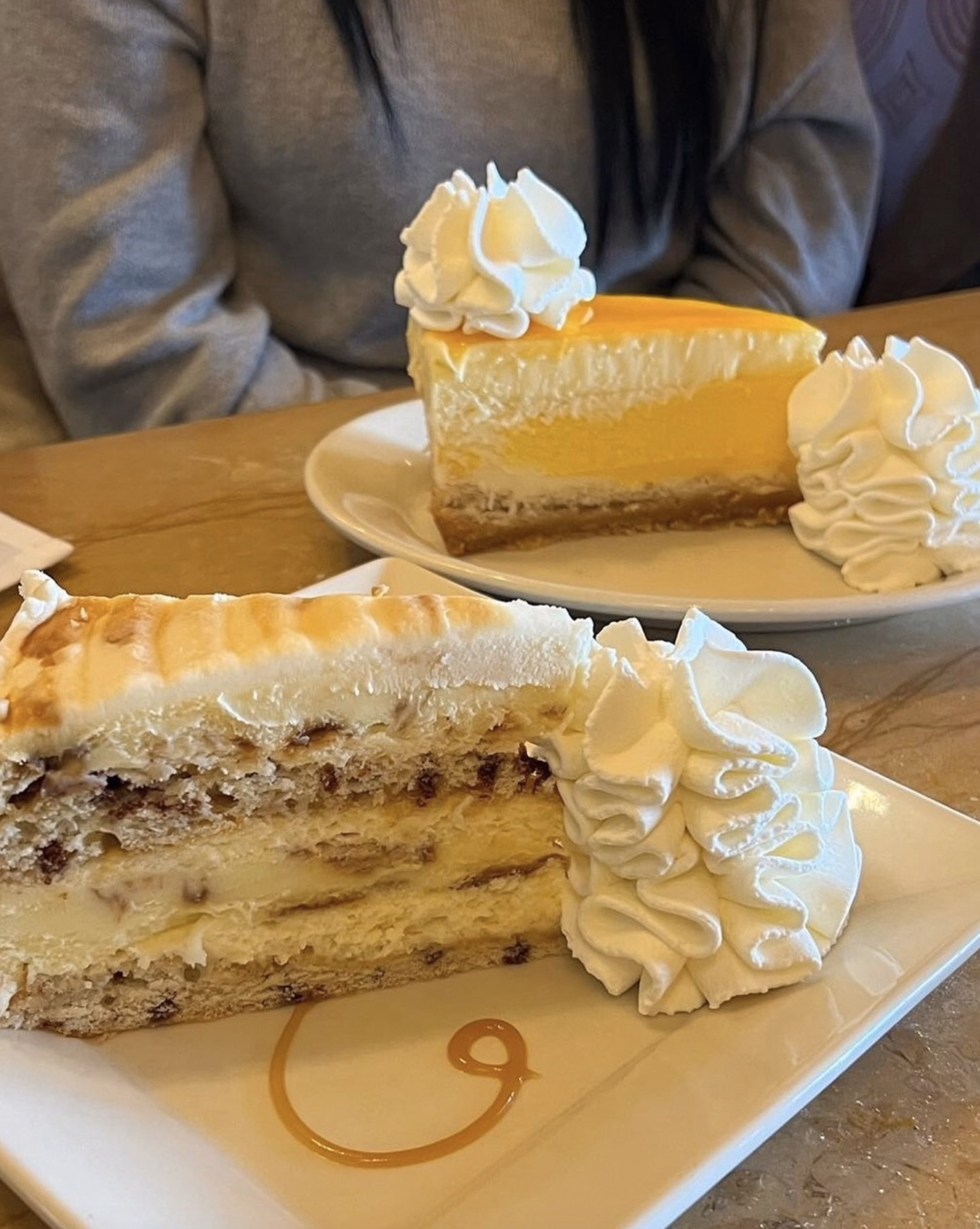 Slices of creamy cheesecake with whipped cream topping.,