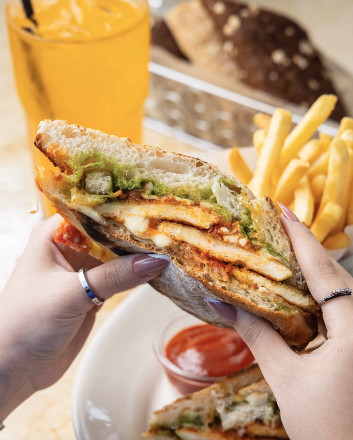 Crispy chicken sandwich with pesto sauce, cheese, and fries.