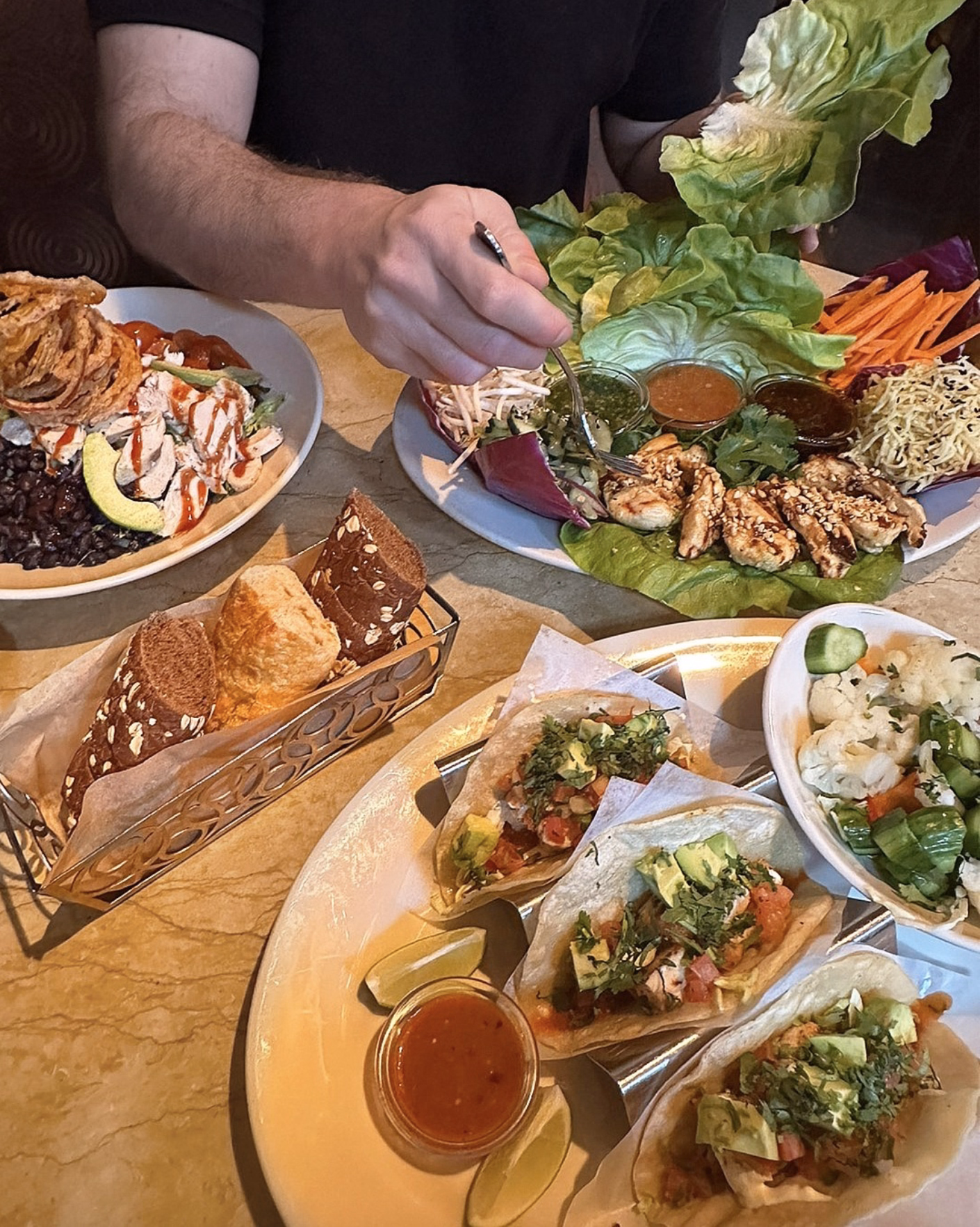 Fresh lettuce wraps and tacos served with colorful sides and sauces.