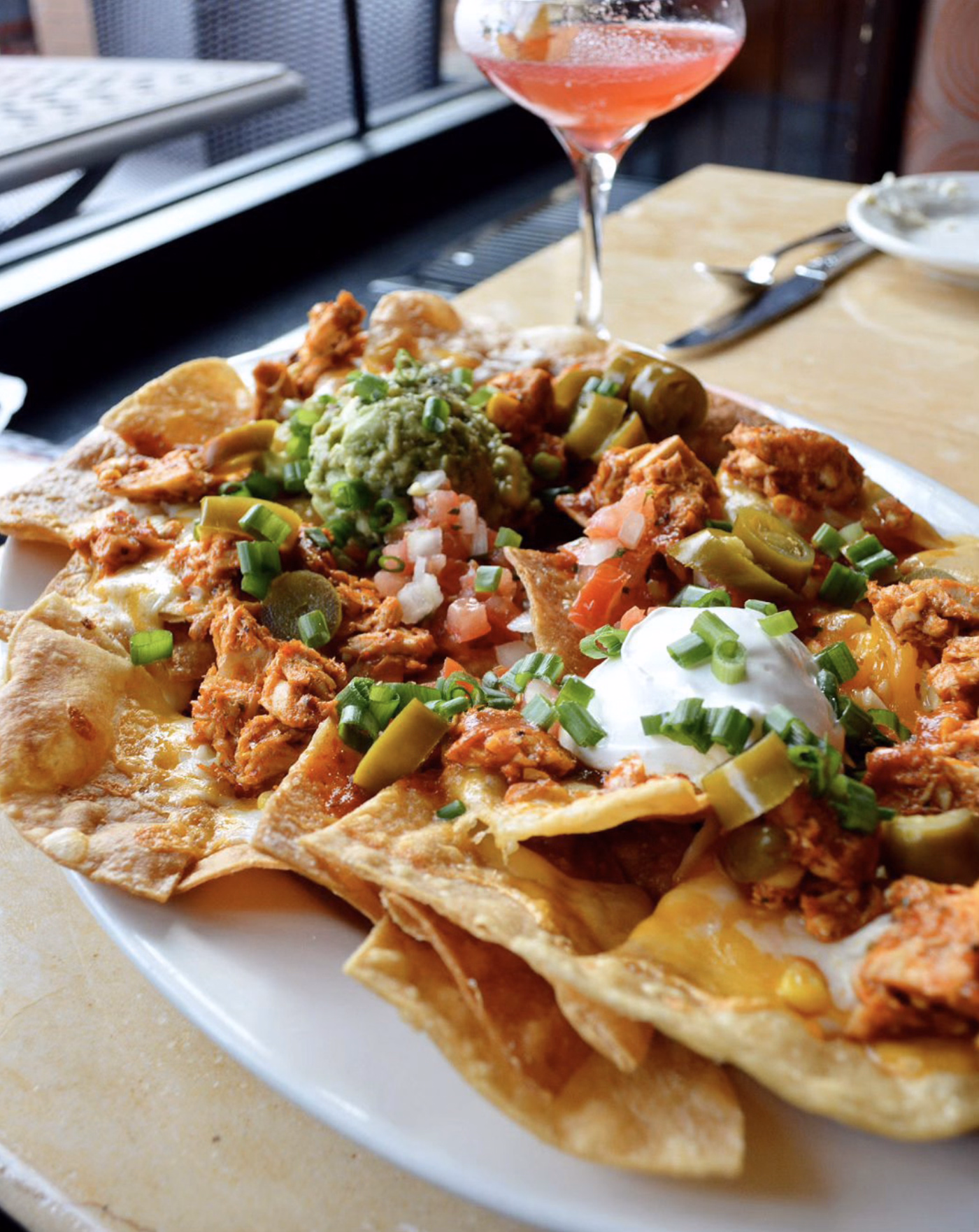 Loaded nachos with chicken, guacamole, and sour cream.