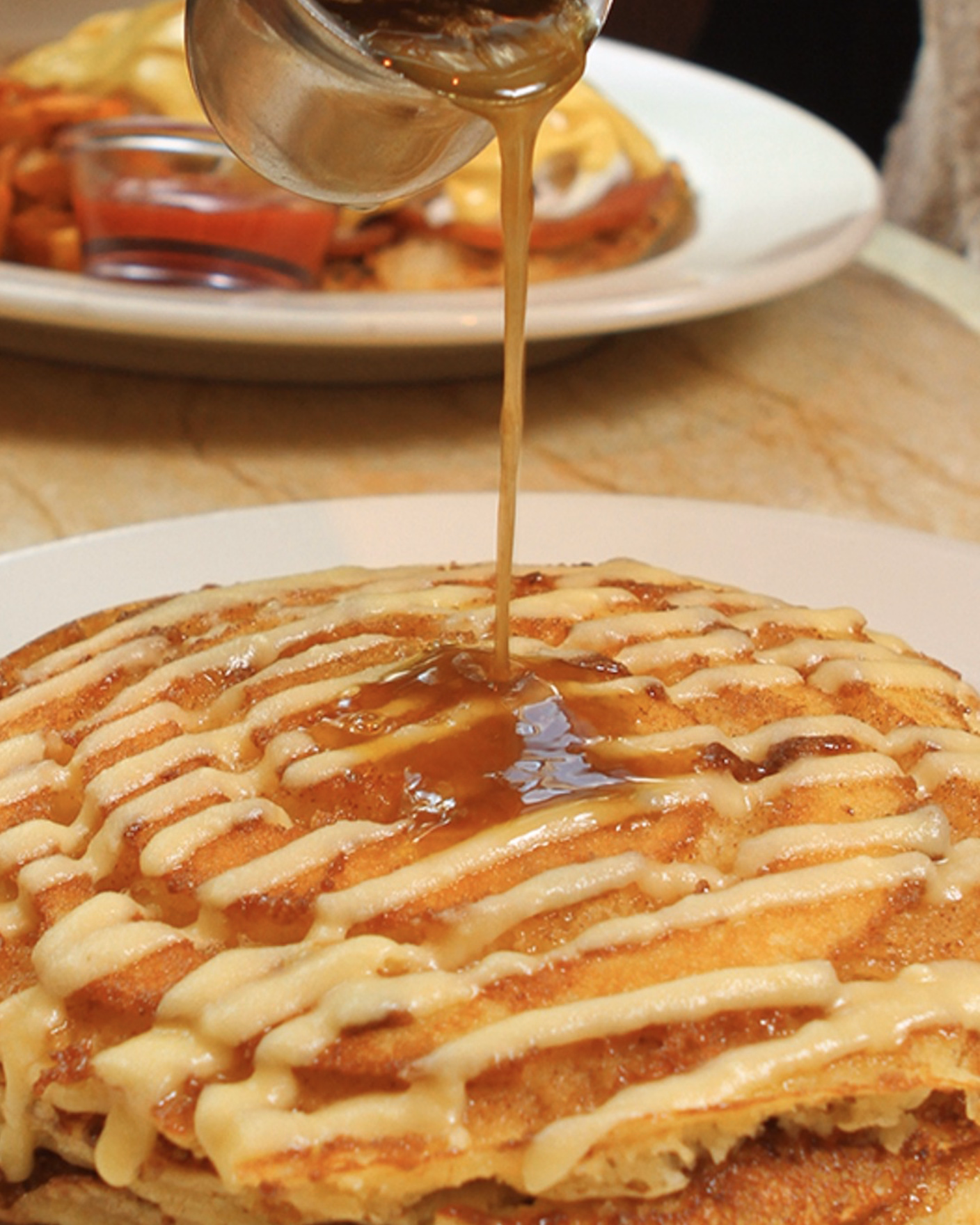 Cinnamon swirl pancakes drizzled with syrup and icing.