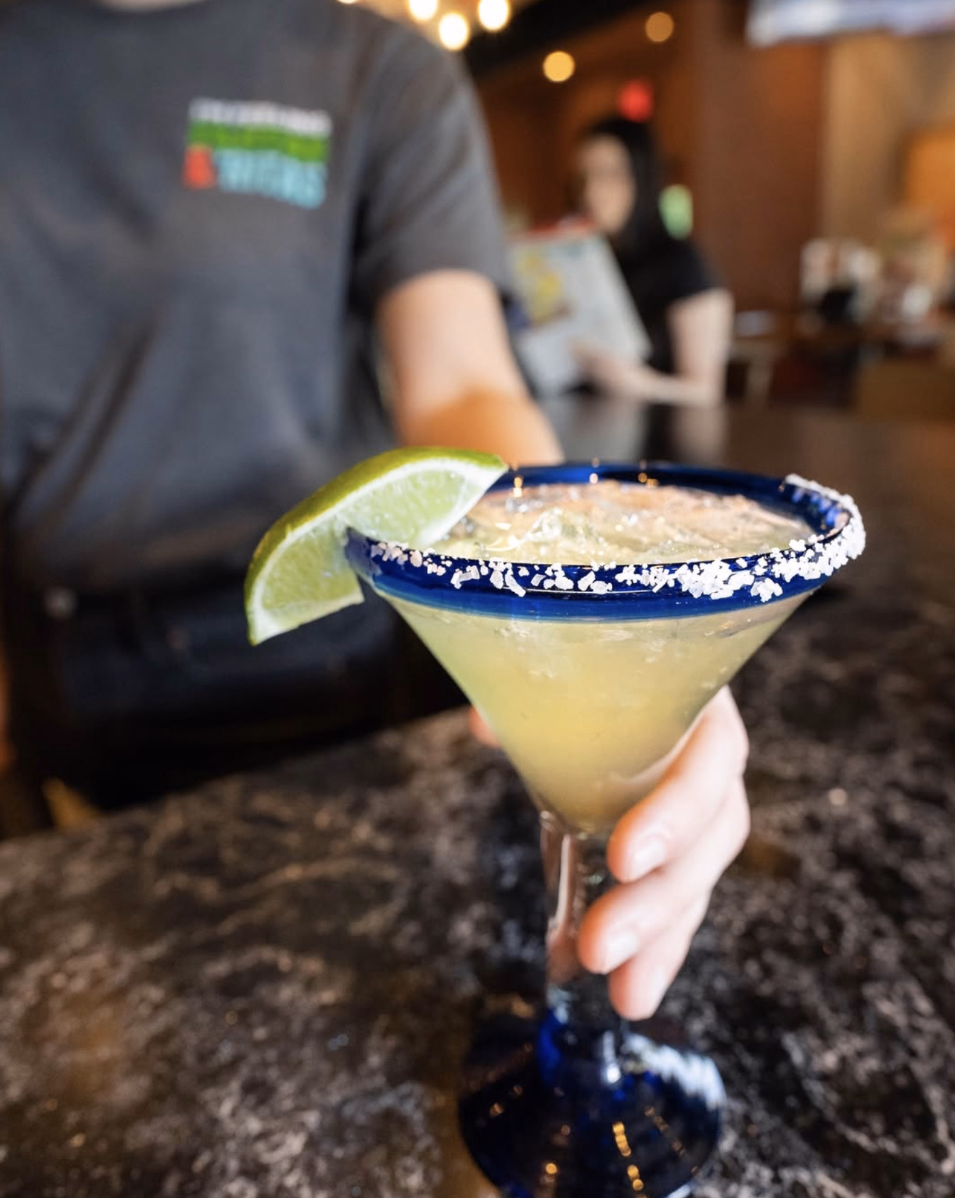 Overhead view of guests raising Chili’s cocktails, including margaritas and mixed drinks, for a celebratory toast.
