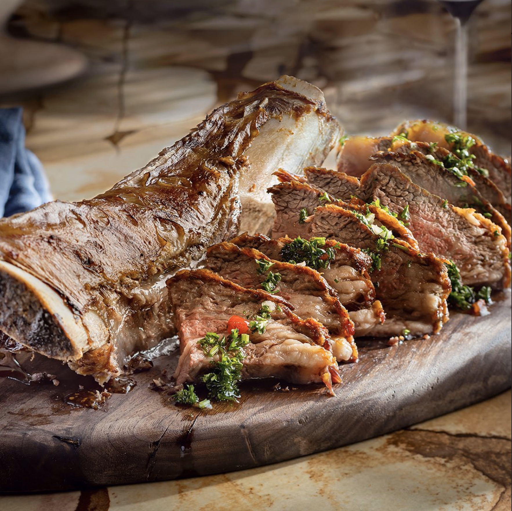 Tender beef ribs with a caramelized crust, sliced and topped with vibrant chimichurri herbs.