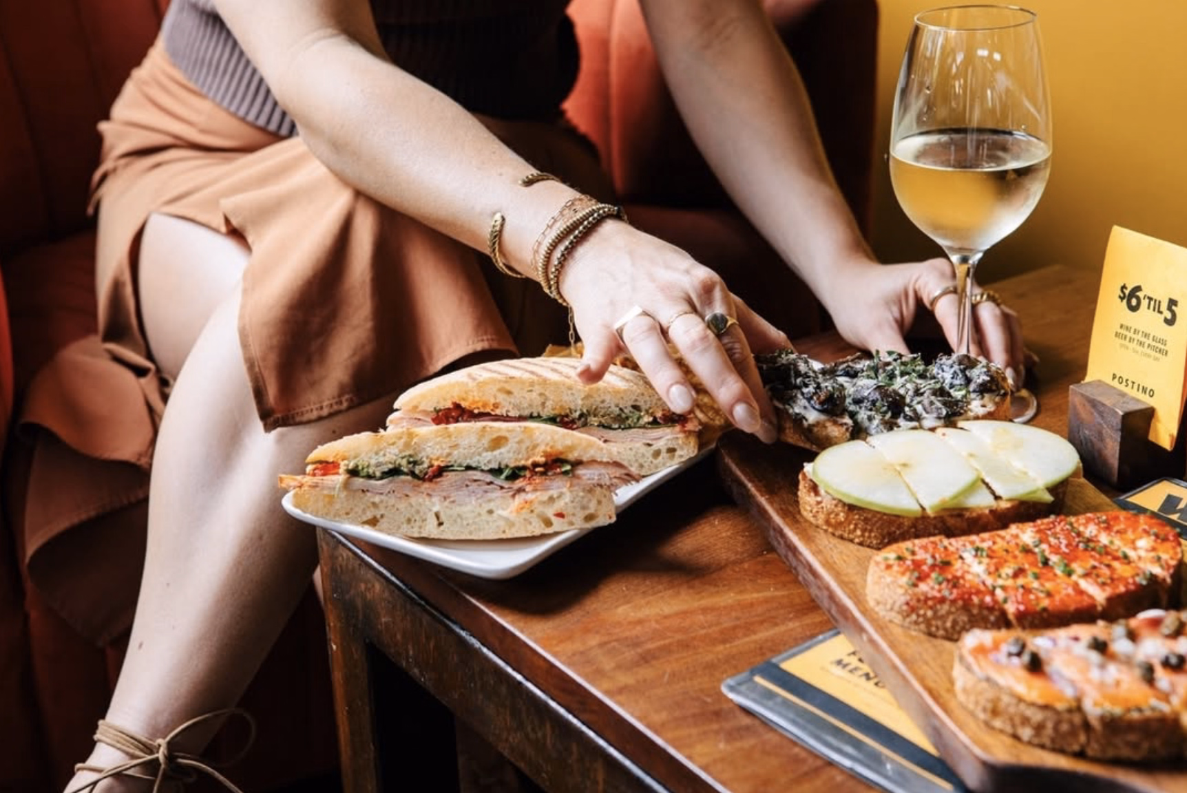 A laid-back setting with layered sandwiches and a crisp glass of white wine.
