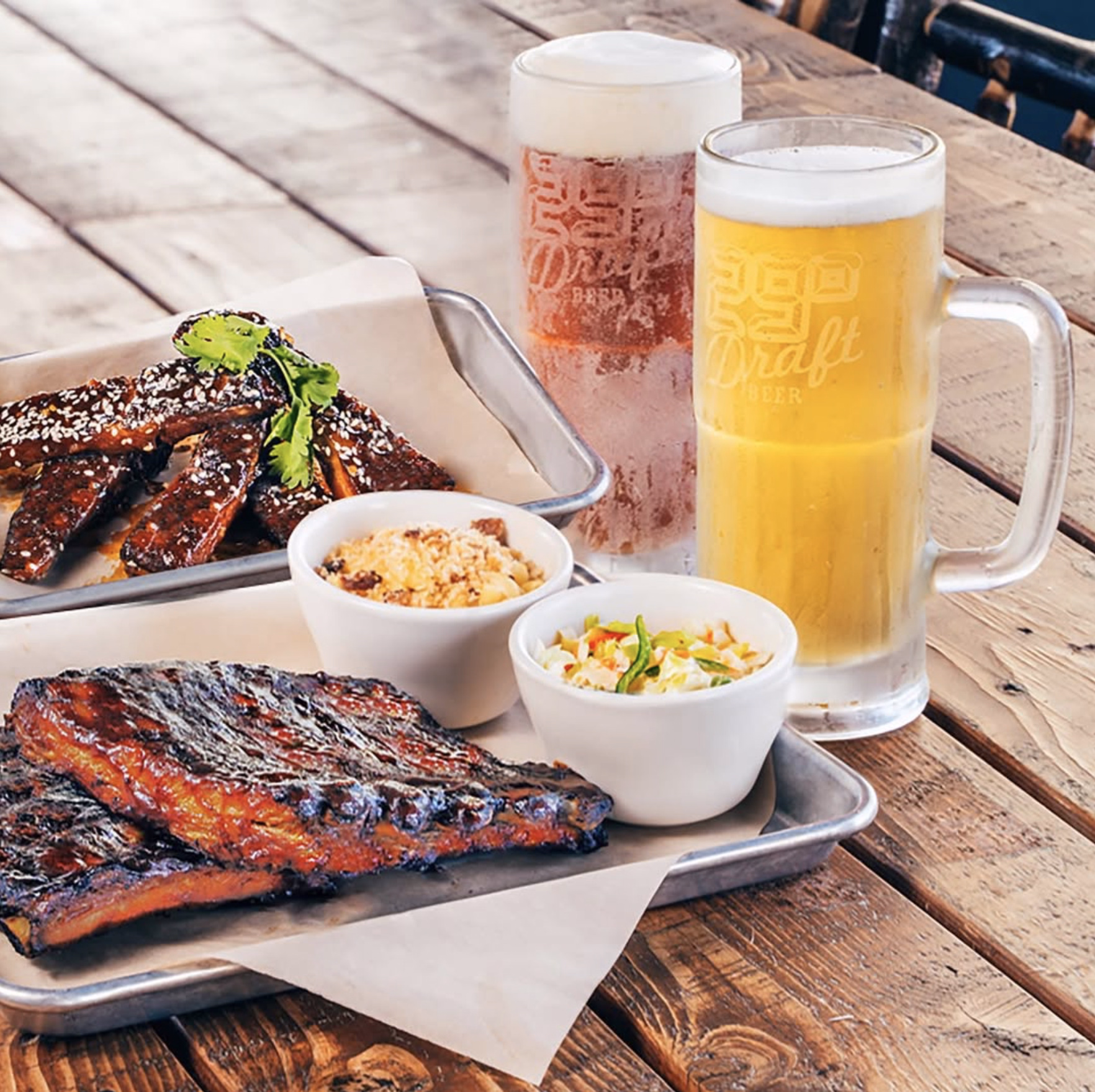 BBQ ribs with sesame glaze, coleslaw, and beer mugs.