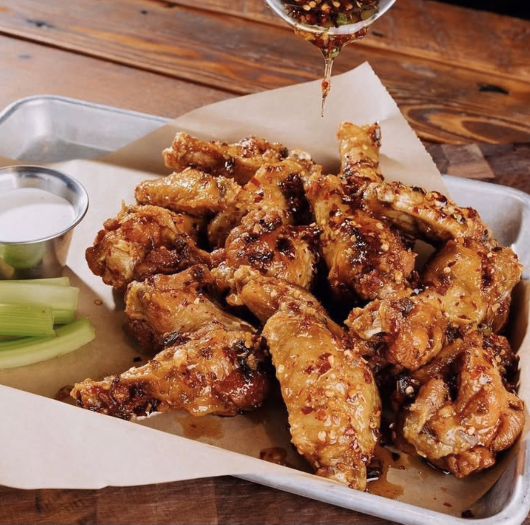 Spicy glazed chicken wings with celery and dipping sauce.