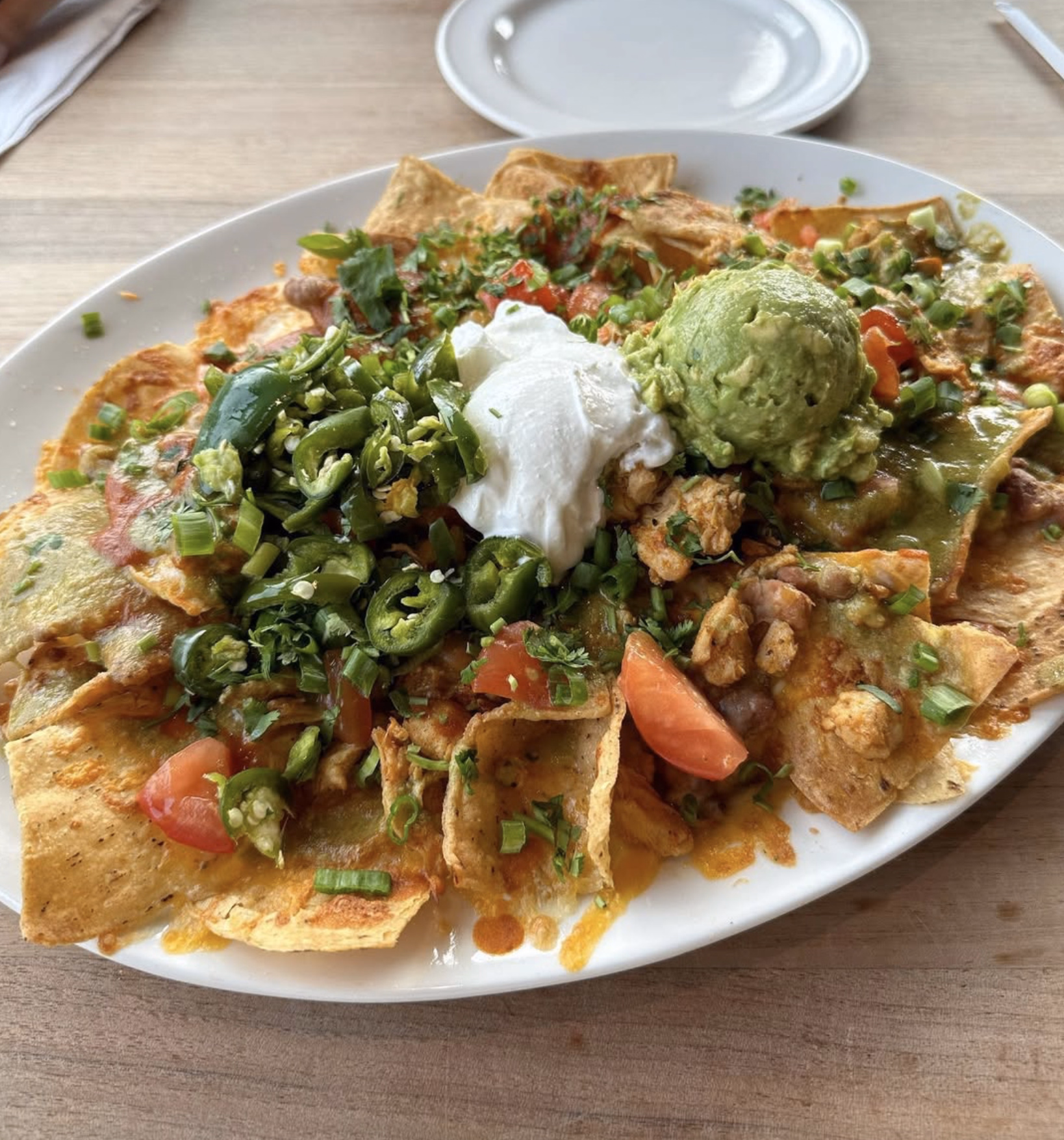 Heaping nachos layered with cheese, veggies, and fresh guacamole.