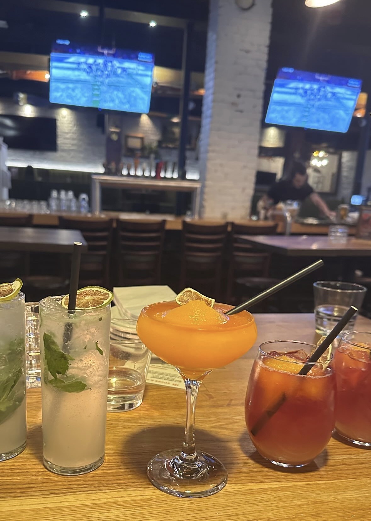 Drinks and televisions on a table in a bar.