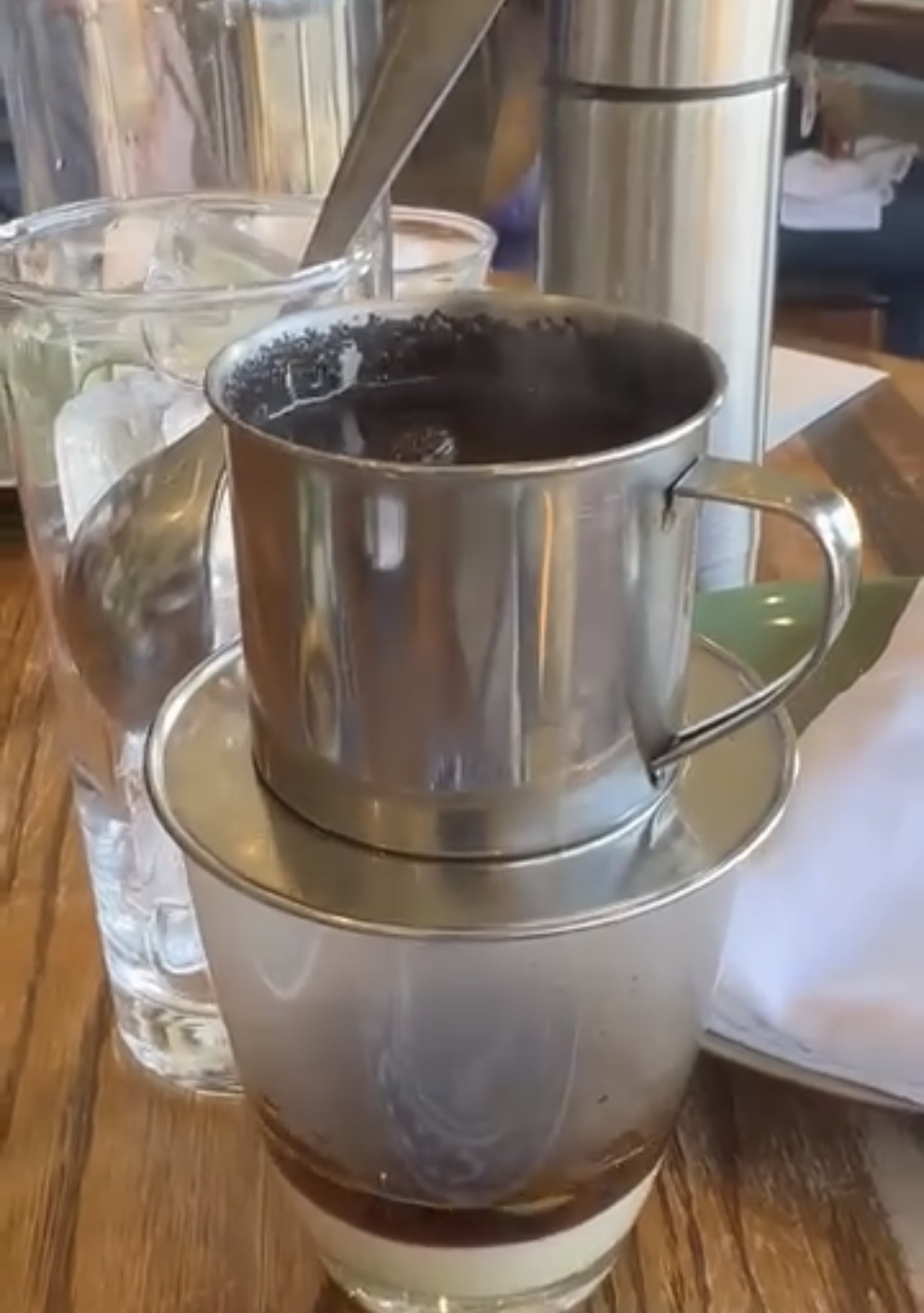 Close-up of a Vietnamese coffee dripper on a glass with condensed milk.