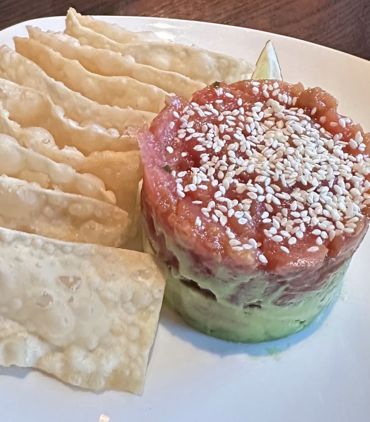 A tuna tartare and avocado stack, topped with sesame seeds and wonton chips.